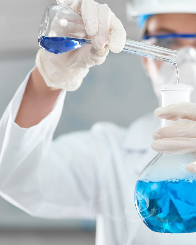 Chemist examining a blue water sample in a laboratory flask